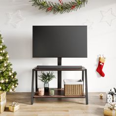 a flat screen tv sitting on top of a wooden shelf next to a christmas tree