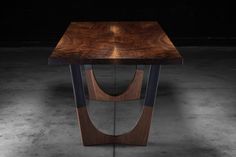 a wooden table sitting in the middle of a room with dark walls and flooring