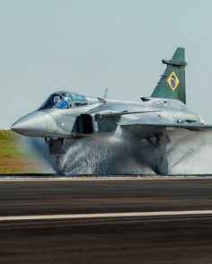 a fighter jet taking off from an airport runway with water splashing on the ground