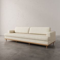 a white couch sitting on top of a cement floor next to a wall and window