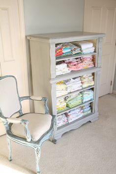 a white chair sitting in front of a dresser