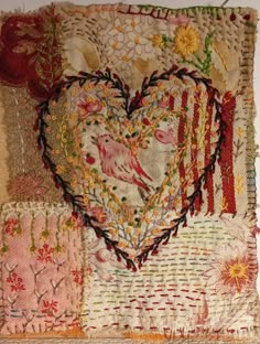 a patchwork heart with flowers and birds on it's side, surrounded by fabric