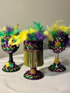 three wine goblets decorated with colorful feathers and beaded trim, on a table