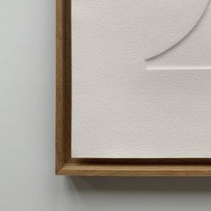 a white piece of paper hanging on the wall next to a wooden frame with a curved corner