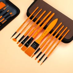 an assortment of orange and black paint brushes in a case with zippered pouch next to it