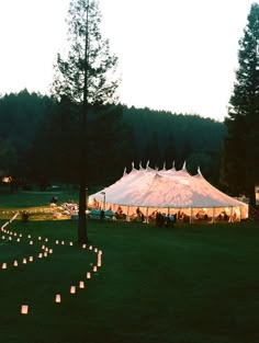 a large tent set up with candles in the grass