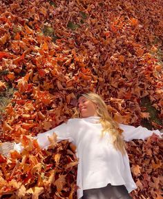 a woman laying on top of a pile of leaves