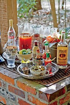 an assortment of alcoholic drinks and condiments on a table in front of a brick wall