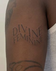 a woman's arm with the word divine feminine written on it, in black ink