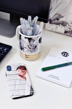 a desk with a cell phone, pen and photo on it