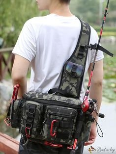 a man is holding his fishing bag while standing by the water