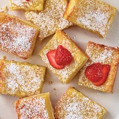 several pieces of french toast with powdered sugar on top and strawberries in the middle