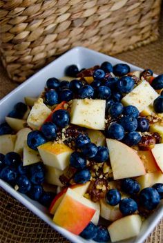 a white bowl filled with blueberries and apples