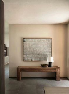 a living room with a large painting on the wall and a wooden table in front of it