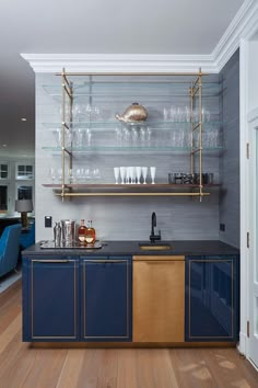 a kitchen with blue cabinets and shelves filled with glasses on top of the cupboards