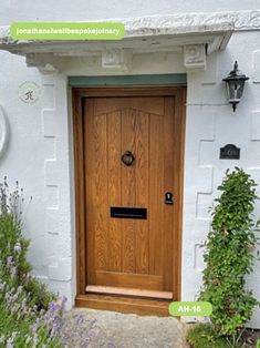 a wooden door in front of a white building with purple flowers and plants around it