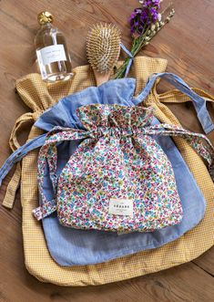 a small bag sitting on top of a wooden floor next to a bottle and flowers