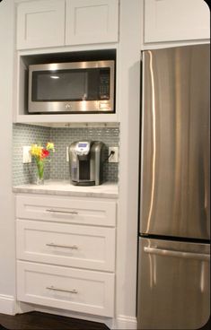 a stainless steel refrigerator freezer sitting next to a microwave oven and coffee maker in a kitchen