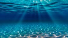 the sun shines through the water as it reflects on the ocean floor with clear blue water