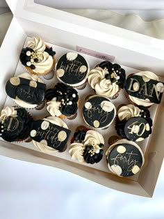 a box filled with cupcakes covered in black and white frosting sitting on top of a table