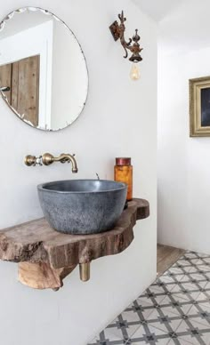 a bathroom sink sitting on top of a wooden counter next to a wall mounted mirror