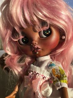 a close up of a doll with pink hair