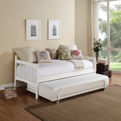 a white day bed sitting on top of a hard wood floor next to a window