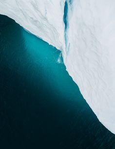 an iceberg in the ocean with blue water and snow on it's sides