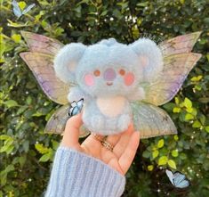 a hand holding a small stuffed animal with wings