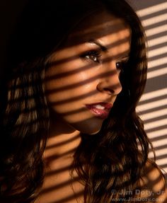 a woman standing in front of a window with the sun shining on her face and hair