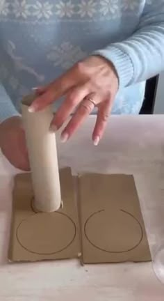 a woman is making some paper circles with her hands on top of the cardboard box