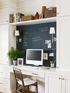 a desk with a computer on top of it in front of a chalkboard wall