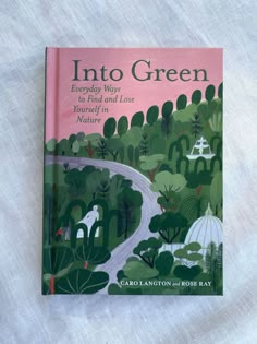 the book into green is laying on top of a white cloth covered tablecloth with an image of a park and trees