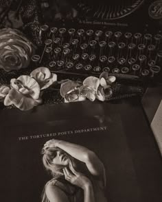 a book with an image of a woman on it next to a typewriter and flowers