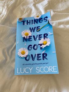 there is a book on the bed with daisies in it that says, things we never got over