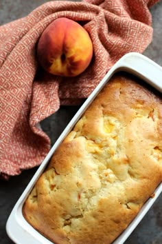 a loaf of peach bread in a pan next to an orange towel and a peach