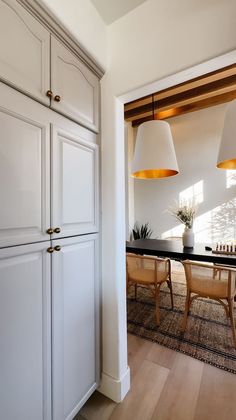 a kitchen with white cabinets and two lamps hanging from the ceiling over a dining room table