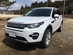 a white land rover is parked in the dirt