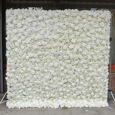 a large white flower covered wall in front of a building