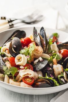 a white bowl filled with pasta and mussels