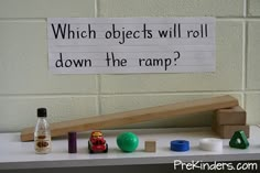 a sign that reads which objects will roll down the ramp? with toys on top