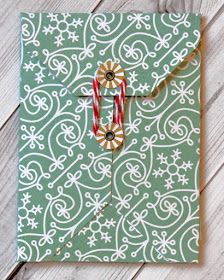 a green and white patterned card with a cross on the front, surrounded by small red and white candy canes