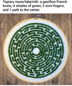 a cross stitch pattern in the shape of a circle with grass growing through it on a wooden surface