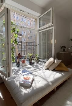 the sun shines through two large windows into a room with a bed and books on it