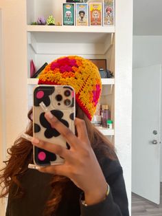 a woman taking a selfie with her cell phone in front of her head and wearing a knitted hat