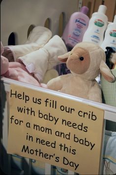 a stuffed lamb sitting next to a sign that says help us fill our crib with baby needs for a mom and baby in need this mother's day