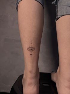 a woman's legs with a small tattoo on her left leg and an eye in the middle