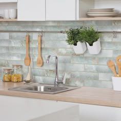 a kitchen sink with wooden spoons and utensils hanging on the wall above it