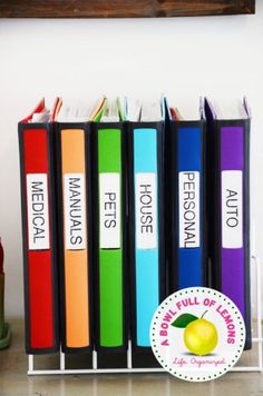 several books are lined up on a shelf next to a wine bottle and an apple