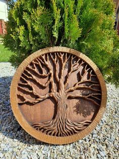 a wooden plaque with a tree carved into it on top of some rocks and gravel